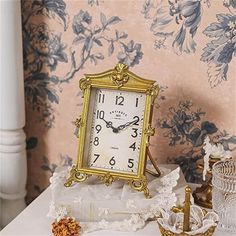 a clock sitting on top of a white table next to a vase and candle holder