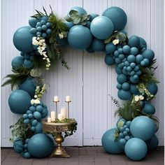 a blue balloon arch with candles and greenery