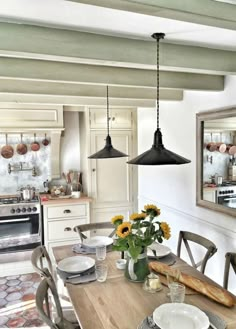 a kitchen table with plates and flowers on it in front of a stove top oven