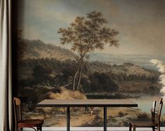 two chairs and a table in front of a wall with a landscape painted on it