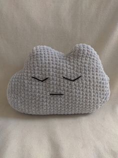 a crocheted cloud pillow with eyes closed on a white bed linens background