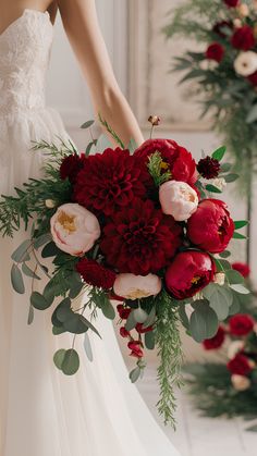 a bride holding a bouquet of red and white flowers