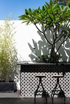 two wooden stools sitting on top of a wooden deck next to a planter