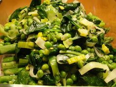 a bowl filled with green vegetables on top of a wooden table