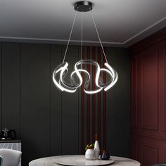 a modern chandelier hanging over a round table in a room with red walls