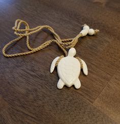 a white turtle ornament on a wooden table with rope around it's neck