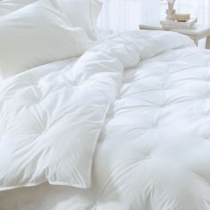 an unmade bed with white comforter and pillows