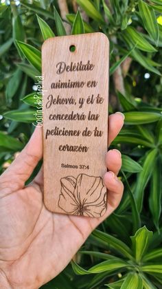 a person holding up a wooden bookmark with a quote on it