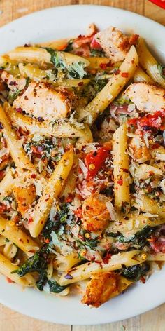 pasta with chicken, spinach and tomato sauce in a white bowl on a wooden table