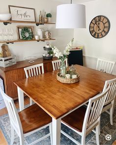 a dining room table with chairs and a clock on the wall above it, along with other furniture