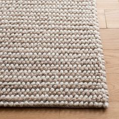 a close up of a rug on the floor with wood floors in front of it