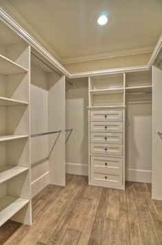 an empty walk in closet with white shelves and drawers