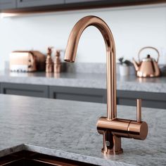 a kitchen with marble counter tops and copper faucet in the middle of it