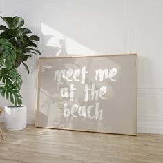 there is a sign that says meet me at the beach next to a potted plant