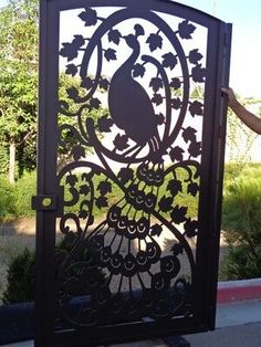 a person standing next to a gate with a peacock on it