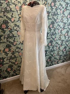 a white dress on display in front of a floral wallpaper