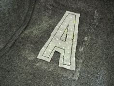 the letter a is made out of felt on top of a piece of fabric that has been sewn onto