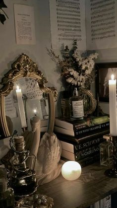 a table topped with lots of books next to a mirror and lit candles on top of it