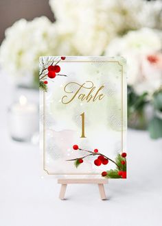 a table number is displayed on an easel with white flowers in the back ground