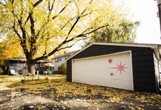 a garage with a flag painted on it in front of a tree and some houses