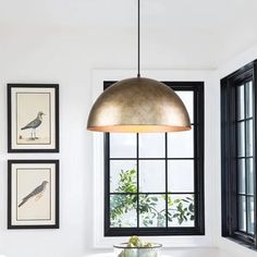 a white table and chairs in a room with pictures on the wall above it, along with a large pendant light