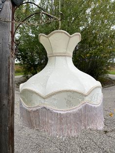 a large white vase hanging from a wooden pole