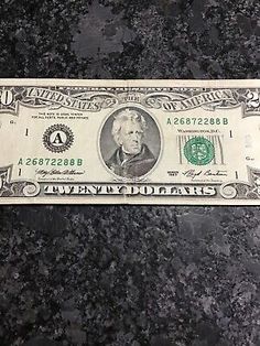 a one dollar bill sitting on top of a black countertop with the word twenty dollars written