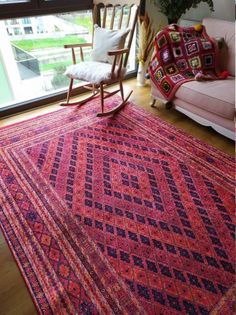 a living room area with a rocking chair and rug on the floor next to a window