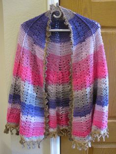 a colorful crocheted jacket hanging on a door