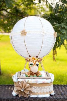 a giraffe sitting on top of a wooden table next to a white balloon