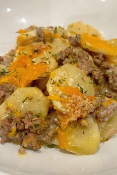 a close up of a plate of food with potatoes and meat in sauce on it