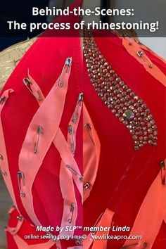 the back of a woman's red dress with pink ribbon and beads on it