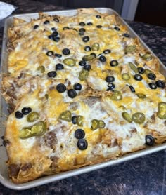 a square pizza with olives and cheese on it sitting on top of a counter