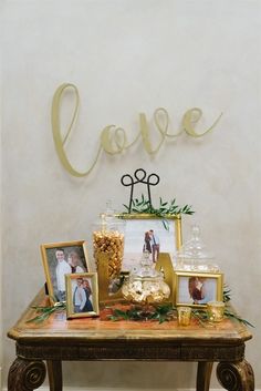 a table topped with pictures and candies next to a love spelled out on the wall