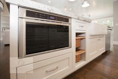 a kitchen with white cabinets and an oven built into the side of the countertop