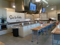 a large kitchen with lots of counter space and tvs on the wall above it