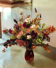 a vase filled with lots of flowers on top of a counter