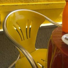 a yellow chair sitting next to a table with an orange cup on top of it