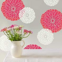 a vase filled with flowers sitting on top of a table next to a white wall