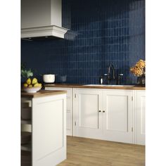 a kitchen with white cabinets and blue tile backsplash, wood flooring and counter tops