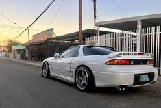 a white sports car parked on the side of the road in front of a building