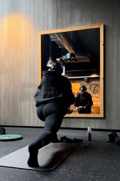 a man is running on a yoga mat in front of a wall with a mirror