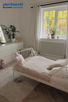 a bedroom with a white bed, dresser and window in it's center area