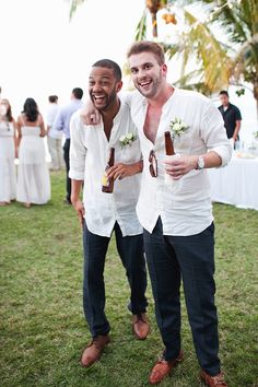 two men standing next to each other holding beer bottles