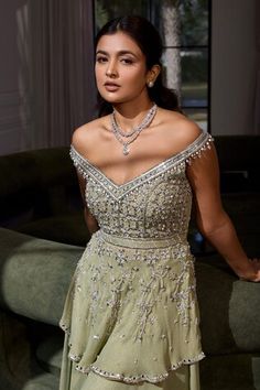 a woman in a green dress posing for the camera with her hand on her hip