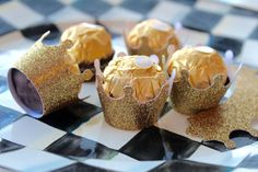 some gold cupcakes are sitting on a checkered table