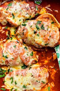 two meatballs covered in sauce and parsley on top of a pan with a spoon