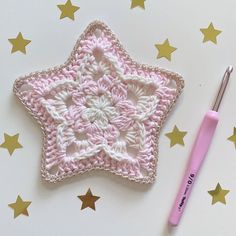 a crocheted star ornament next to a pink crochet hook