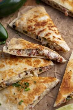 several quesadillas cut in half on a cutting board with jalapenos