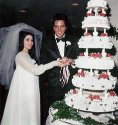 a bride and groom standing next to a wedding cake